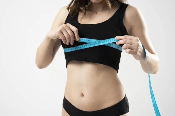 Corpo feminino saudável com fita métrica. A menina tomando medidas de seu corpo no fundo branco. — Fotografia de Stock