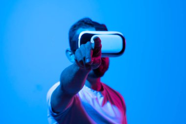 Çekici sakallı bir adam sanal gerçeklikle sanal gerçeklik deneyimi yaşıyor ve siber uzayda gördüğü bir şeye elleriyle dokunmaya çalışıyor. Metaverse ve oyun konsepti.