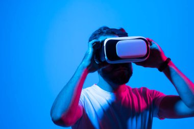 Yüksek teknolojili VR gözlükler takan, 360 derecelik video izleyen ya da arkadaşlarıyla video oyunu oynayan şaşkın sakallı bir gencin portresini yakından çek..