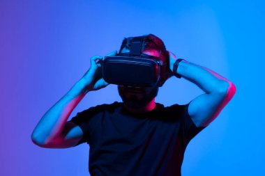 Genç sakallı oyuncu arkadaşlarıyla sanal gerçeklik kaskıyla online video oyunu oynuyor. Oyun kurgusal dünyada davranışları, aletleri ve sanal gerçeklik bağımlılığını taklit eder. Gelecekteki teknoloji konsepti.