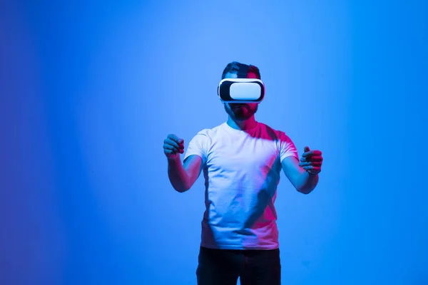 El hombre usa un auricular VR y se para mientras sostiene algo en el espacio virtual. Tecnología del futuro, juego en línea, realidad virtual, entretenimiento, estudio, simulación 3D y mundo virtual. — Foto de Stock