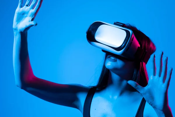 Fiatal nő áll a stúdióban visel VR szemüveg és lopás görgetés zooming kézzel egy virtuális térben, miközben kölcsönhatásba lépnek a tárgyakat egy metaverzumban. Virtuális valóság technológia. — Stock Fotó