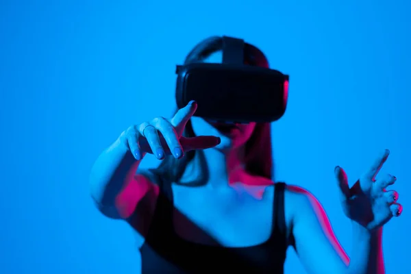 Młoda brunetka w czarnym t-shircie w okularach VR współpracuje z cyberprzestrzenią za pomocą przesuwnych i rozciągających się gestów podczas pracy nad projektem. — Zdjęcie stockowe