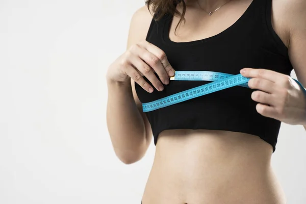 Krásná sportovní štíhlá mladá žena měření její velikost postavy s páskou opatření. Ženy drží centimetr a měří prsa s modrou měrnou páskou. — Stock fotografie