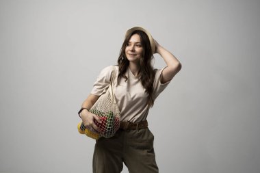 Kopya alanı ile sıfır atık kavramı. Yeniden kullanılabilir bir alışveriş çantası taşıyan sebzeli, ürünlü bir kadın. Çevre dostu ağ tüccarı. Sıfır atık, plastiksiz konsept.