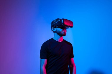 Sanal gerçeklik kasklı genç sakallı adam internette metaverse olarak oyun oynuyor. Oyun kurgusal dünyada davranışları, aletleri ve sanal gerçeklik bağımlılığını taklit eder. Gelecekteki teknoloji konsepti.