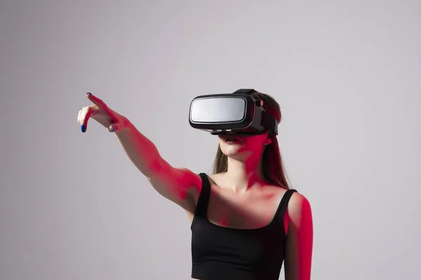 Barna nő egy fekete pólóban és VR headset nézett fel, és megpróbálja megérinteni tárgyak virtuális valóság. A VR olyan technológia, amely fizikai jelenlétet szimulál és kölcsönhatásba lép a környezettel. — Stock Fotó