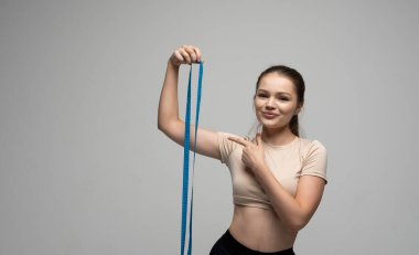 Güzel, güzel, çekici, mutlu, sağlıklı, esmer, spor kıyafetli bir kadın elinde mavi bir bant tutuyor..