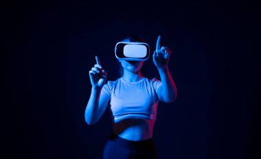 Modern mimar iş yerinde sanal gerçeklik gözlüğü kullanıyor. VR gözlüklü bir kadın neon ışıkta çalışıyor. VR stüdyosunda çalışan tasarımcı.
