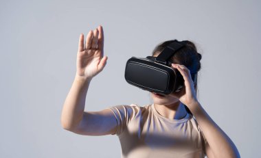 Stüdyoda VR gözlüklü ve elleri havada kaydıran genç bir kadın var. Sanal gerçeklik teknolojisi.