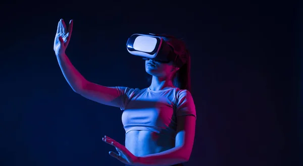 Modern építész virtuális valóság szemüveg a munkahelyen, és megérint valamit a virtuális világban. Egy nő VR szemüvegben dolgozik neon fényben. VR stúdióban dolgozó tervező. — Stock Fotó
