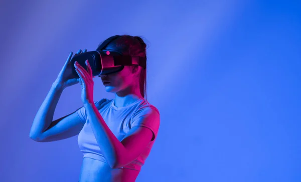 Kobieta doświadcza wirtualnej rzeczywistości gogle w świetle neonu. — Zdjęcie stockowe