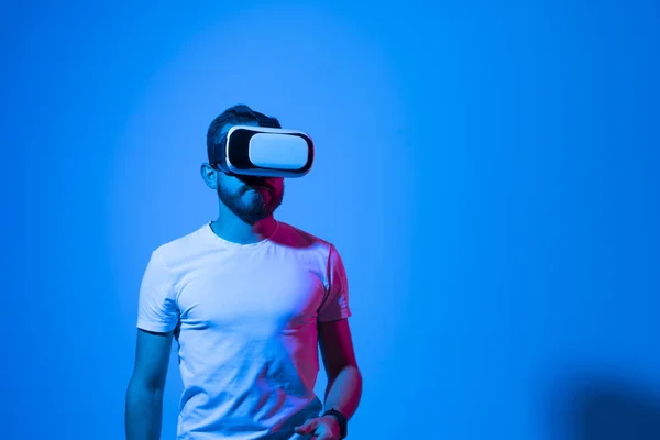 Joven barbudo con gafas de realidad virtual e interactuando con un entorno virtual. Concepto de tecnología futura. Metaverso. — Foto de Stock