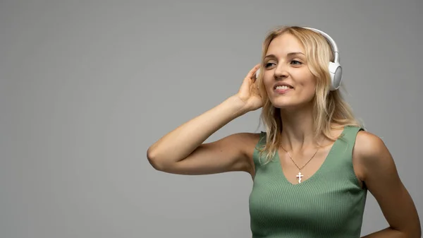 Hermosa chica rubia en camiseta verde en auriculares divirtiéndose en el estudio bailando y riendo. —  Fotos de Stock