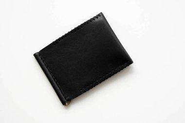 Siyah adamların para klipsleri, el yapımı deri cüzdan. Kağıt oynamak için iki cebi olan boş para klipsli cüzdan beyaz bir masada yatıyor. Seçici odak, boşluğu kopyala.