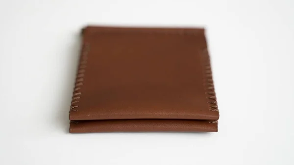 Оранжевый мужской клип ручной работы кожаный бумажник. Пустой кошелек с двумя карманами для карт лежит на белом столе. Выборочный фокус, копировальное пространство. — стоковое фото