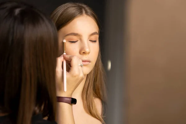 Proffesional make-up artist applying eyeshadow powder on a models eyes in beauty studio. — Stock Photo, Image