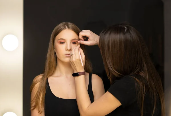 Makeup artist applying liquid tonal foundation on the face of the woman in make up room. — Stock Photo, Image