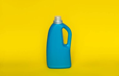 Sarı arka planda izole edilmiş mavi plastik şişedeki yumuşatıcı. Sıvı çamaşır deterjanı, temizlik maddesi, çamaşır suyu ya da yumuşatıcı içeren bir şişe. Ürün tasarımı. Model