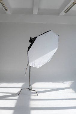 Modern bir fotoğraf stüdyosunun simülatörünün üstünde kocaman pencereleri olan bir sehpanın üzerinde oktav ışığı olan profesyonel bir fotoğraf feneri. Profesyonel ışıklandırma ekipmanları, flaşlar, C-standları