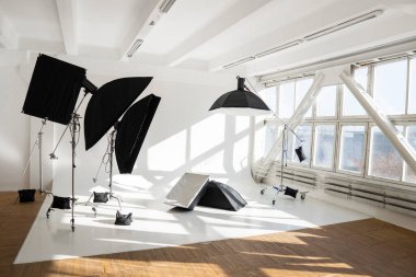 Profesyonel ışıklandırma ekipmanları, flaşlar, dev pencereli modern bir fotoğraf stüdyosunun siklonamaları. Octabox, strikbox, softbox, buety plakası ve fotoğraf için diğer şeyler