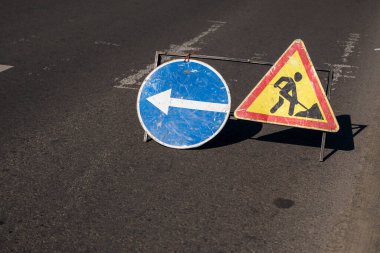 Yol çalışmaları hakkında mavi ve sarı-kırmızı güvenlik işaretleri. Yol yapım ya da onarım aşamasında. Araç yolunun ortasında tamirat işi, seçici odaklanma.
