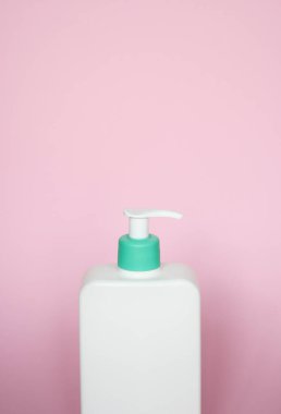 Pompa pompalı büyük beyaz plastik şişe ve pembe arka planda yeşil kapak. Jöle, losyon, krem, şampuan, banyo köpüğü için sıvı kap.