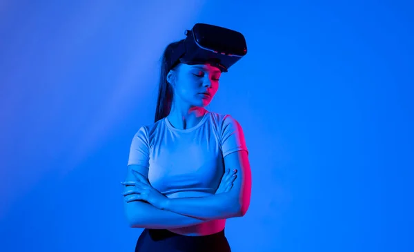 Portrait of young woman with a glasses of virtual reality in neon light. VR, augmented reality, science, future technology concept. Futuristic 3d glasses with virtual projection