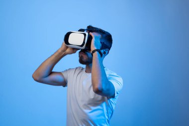 Sakallı genç adam VR gözlük kullanıyor, el fotokopi alanı ile dokunuyor, arkadaşlarıyla sanal video oyunları oynuyor.