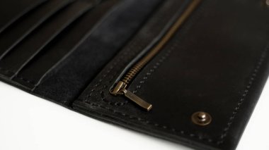 Details of mans handmade wallet on a white surface. Wallet made of genuine black leather with a slots for cards and big zip pocket on a white background. Accessories for men