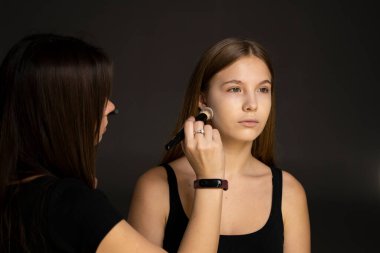 Proffesional makyaj sanatçısı güzel model yüzüne makyaj yapar. Güzel manken.