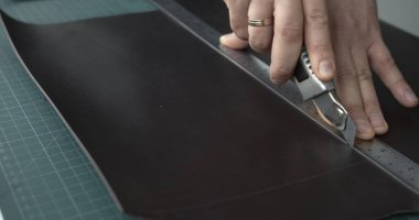 Deri atölyesinde yeni bir el yapımı deri cüzdan yapan bir ustanın elleri. Deri ürünleri üretmek için küçük işletme kavramı