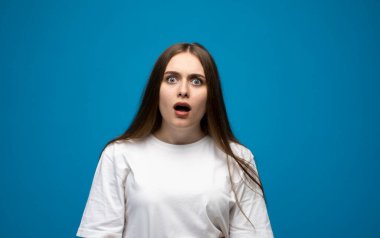 Mutsuz bir esmer kadının portresi. Mavi arka planda tek başına dikilip aşağıya bakıyor.