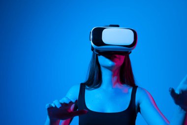 Woman using VR virtual reality glasses headset pointing at objects in metaverse. Virtual reality metaverse