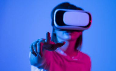 Woman in VR goggles relaxing and playing a video game with a friends in metaverse in studio. The concept of metaverse, virtual reality, future, technology