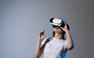 Woman in VR headset using finger to touch on imaginary panel viewing on VR device. VR is a computer technology that simulates a physical presence and allows to interact with environment