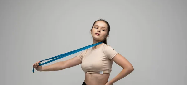Diet, sport and heath concept. Beautiful brunette sporty woman with measuring tape. Athletic slim woman measuring her body by measure tape after a diet