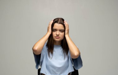Portrait of stressed beautiful brunette woman holding her head with hands having headache. Attractive female suffering from head pain