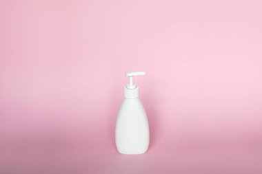 White plastic bottle with white dispenser, isolated on pink background