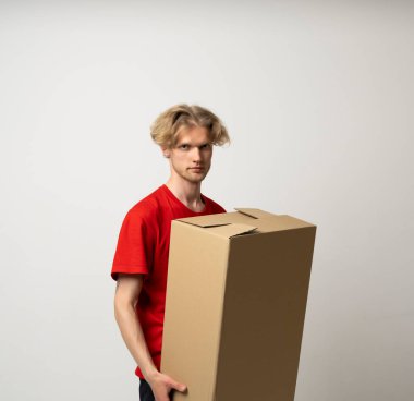 Kırmızı üniformalı mutlu bir teslimatçının portresi beyaz arka planda izole edilmiş bir posta kutusuyla duruyor.