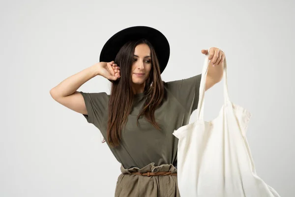 Young woman in a green t-shirt and black hat with white cotton bag