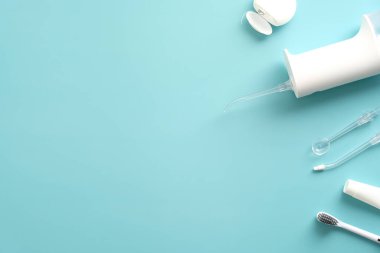 Diş ürünleri mavi arka planda. Düz su yatıyordu. Ağız temizleyici, diş macunu, diş fırçası ve diş ipi.
