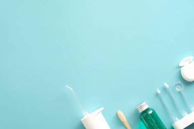 Mavi arka planda diş bakımı ürünleri. Su temizleyici, ağız gargarası, diş ipi, diş fırçası ile düz konum.