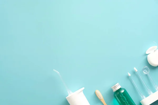 Dental care products on blue background. Flat lay composition with water flosser irrigator, mouthwash, dental floss, toothbrush.