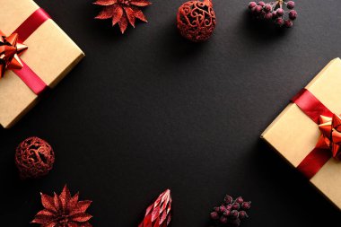 Hediyeli Noel çerçevesi, kırmızı süslemeler, siyah arka planda toplar. Düz konum, üst görünüm, kopyalama alanı. Noel afişi modeli, yeni yıl kartpostal şablonu