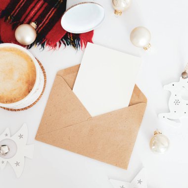 İçinde noel mektubu maketi olan el işi kağıt zarf, bir fincan kahve, eşarp, beyaz masa üzerinde İskandinav Noel süslemeleri. İskandinav Noel konsepti.