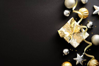 Altın ve gümüş topları ve yıldızları olan siyah Noel arkaplanı, hediye kutusu. Lüks Noel tebrik kartı tasarımı, afiş modeli. Düz konum, üst görünüm, kopyalama alanı.