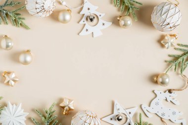 Noel kompozisyonu. Eski yılbaşı dekorasyonları ve bej arka planda köknar dallarından yapılmış bir çerçeve. Düz konum, üst görünüm, kopyalama alanı.