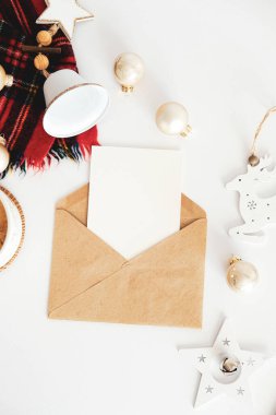 Noel mektubu maketi. Kağıt üzerinde boş kağıt ve beyaz masa üzerinde Xmas süsleri olan el işi bir zarf. Düz konum, üst görünüm, kopyalama alanı.