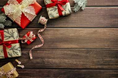 Noel arkaplanı hediye kutuları, köknar dalları, ahşap masa üzerindeki klasik kurdele. Üst manzara, düz yatış. Xmas ya da Yeni Yıl tebrik kartı tasarımı.